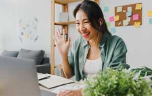 Woman waving from home office on her laptop connecting with her comprehensive EAP via video telehealth.