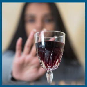 Alcohol use during the holidays can pose a high risk.. Woman saying no to a glass of red wine.