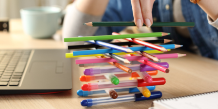 Woman stacking pens instead of focusing and doing her job.